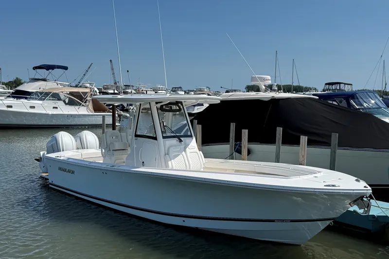 Slide: The Image of 2024 Regulator 28 boat docked in marina, surrounded by other vessels under clear blue sky. - 22