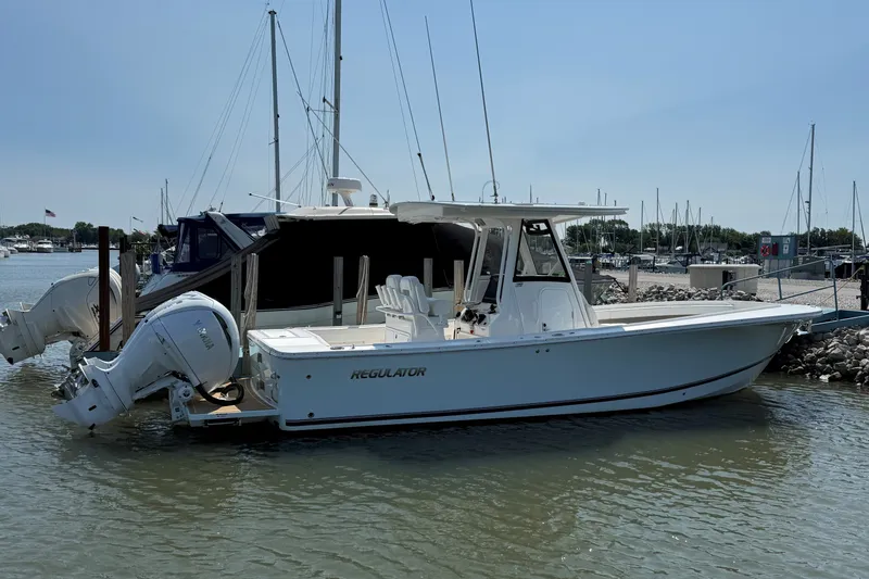 Slide: The Image of 2024 Regulator 28 boat docked at marina with twin outboard engines. - 24