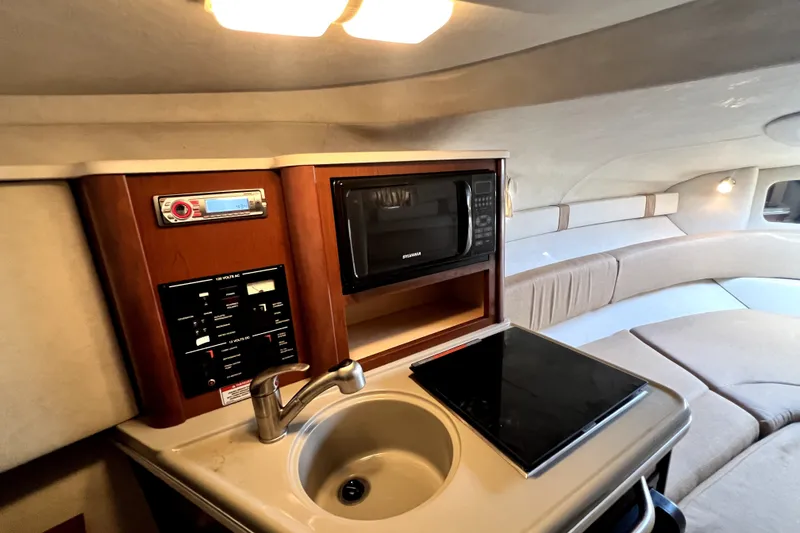 Slide: The Image of 2010 Sea Ray 240 Sundancer cabin with kitchenette, microwave, and seating area. - 65