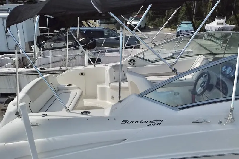 Slide: The Image of 2010 Sea Ray 240 Sundancer boat with canopy, parked in a marina. - 89