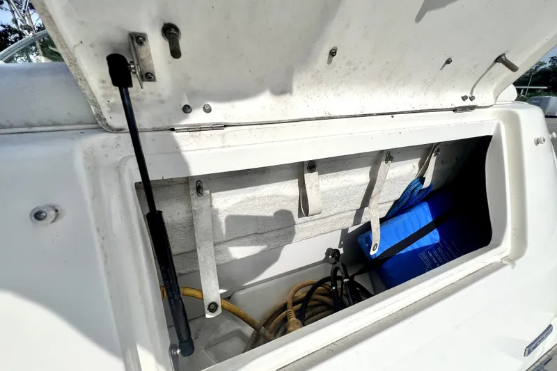 Slide: The Image of Open storage compartment on a 2010 Sea Ray 240 Sundancer boat, containing ropes and equipment. - 64