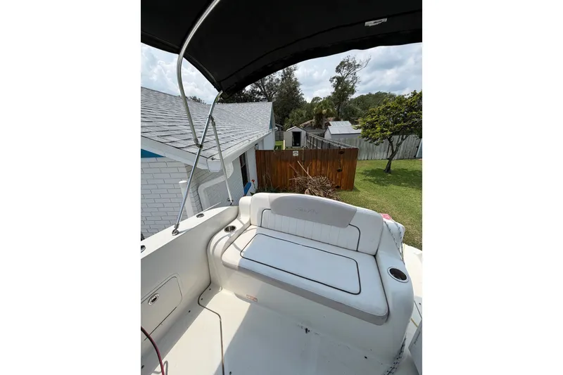 Slide: The Image of 2010 Sea Ray 240 Sundancer boat with cushioned seating and canopy in a backyard setting. - 7