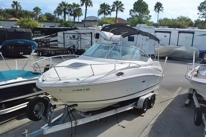 The Image of 2010 Sea Ray 240 Sundancer boat on trailer, parked near RVs and palm trees. - 0