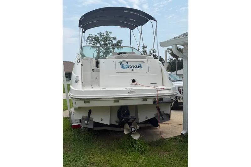 Slide: The Image of 2010 Sea Ray 240 Sundancer boat parked on grass with canopy. - 2