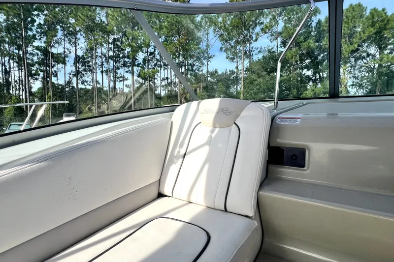 Slide: The Image of Interior of 2010 Sea Ray 240 Sundancer boat with white seating and forest view. - 46