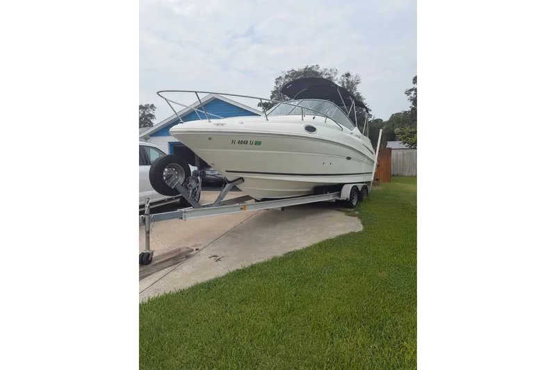 Slide: The Image of 2010 Sea Ray 240 Sundancer boat on trailer, parked in driveway near grass. - 1