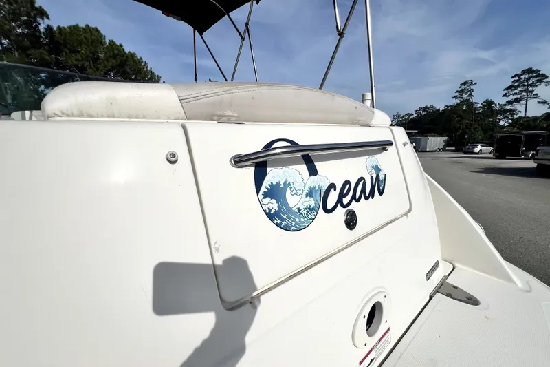 Slide: The Image of 2010 Sea Ray 240 Sundancer boat with "Ocean" decal, parked outdoors under clear sky. - 66