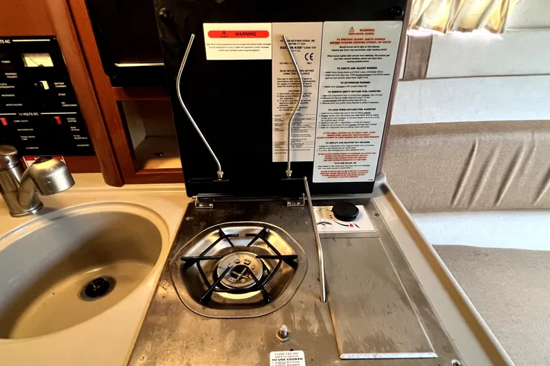 Slide: The Image of 2010 Sea Ray 240 Sundancer interior with stove and sink in compact kitchen area. - 72