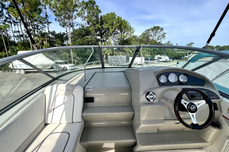 Slide: The Image of 2010 Sea Ray 240 Sundancer cockpit with steering wheel and dashboard, parked outdoors. - 40
