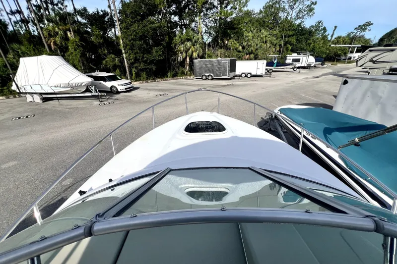Slide: The Image of 2010 Sea Ray 240 Sundancer boat parked in a marina with trailers and trees. - 39