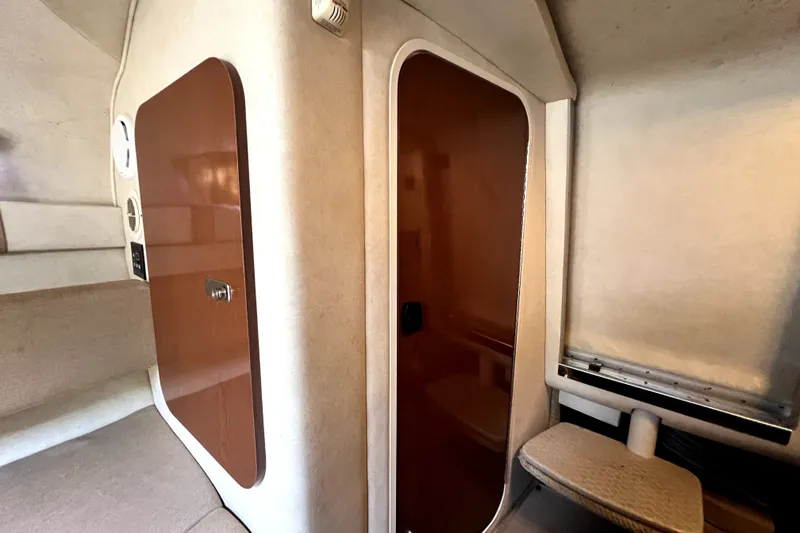 Slide: The Image of Interior cabin of 2010 Sea Ray 240 Sundancer with wooden door and beige upholstery. - 74