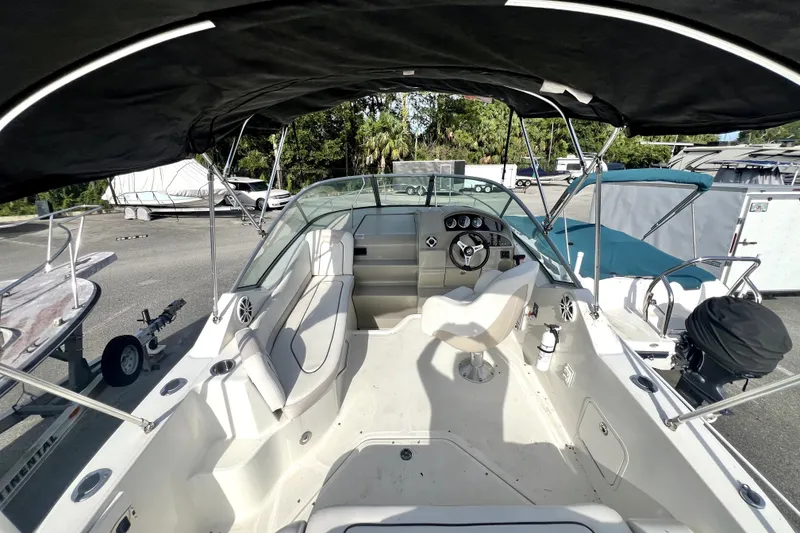 Slide: The Image of 2010 Sea Ray 240 Sundancer boat interior with helm, seating, and canopy in a marina setting. - 50