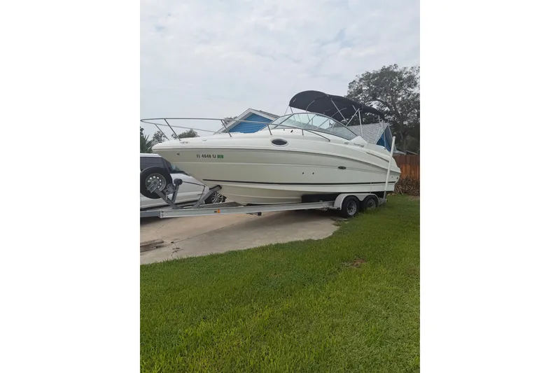 The Image of 2010 Sea Ray 240 Sundancer boat on trailer, parked on grass. - 0