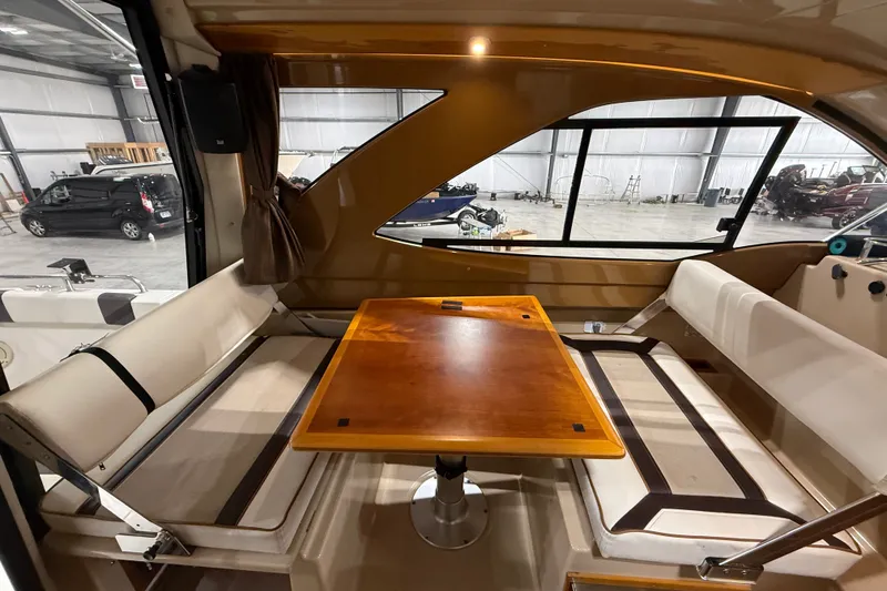 Slide: The Image of Interior of a 2016 Cutwater C-24 boat with a wooden table and cushioned seating. - 24