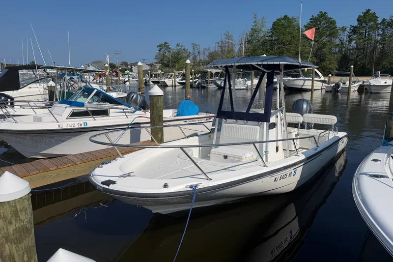 The Image of 2001 Boston Whaler 220 Dauntless docked at marina, surrounded by other boats. - 1