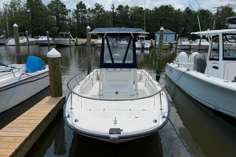 Slide: The Image of 2001 Boston Whaler 220 Dauntless docked at a marina, surrounded by other boats. - 2