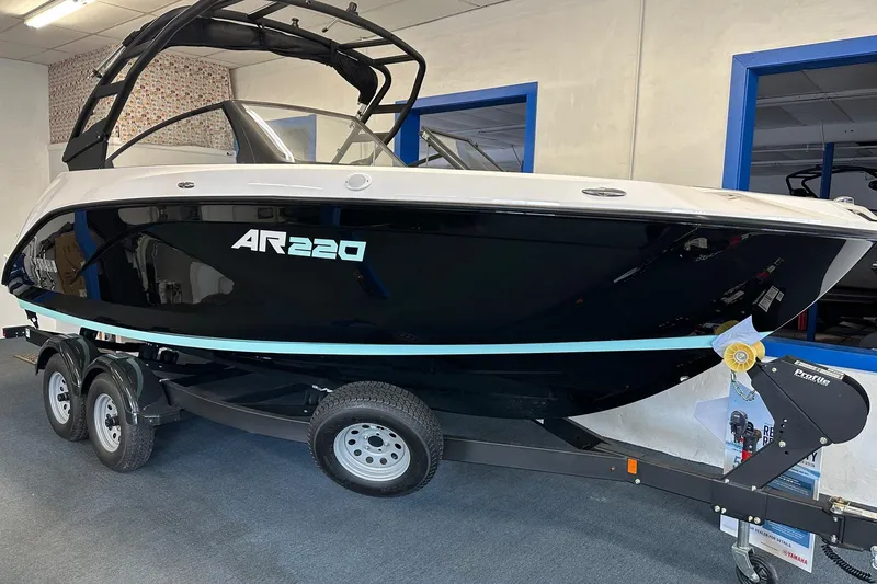 Slide: The Image of 2026 Yamaha Boats AR220 on trailer in showroom, sleek black and white design. - 2