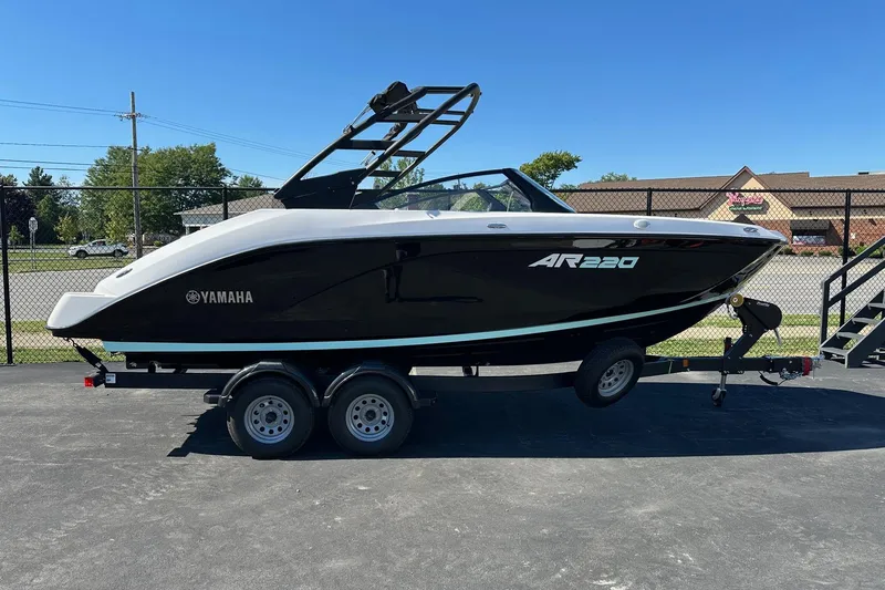 The Image of 2026 Yamaha Boats AR220 on trailer, sleek black design, parked outdoors. - 0