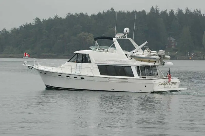 Slide: The Image of 2000 Bayliner 4788 Pilot House Motoryacht cruising on a calm lake with forested background. - 2