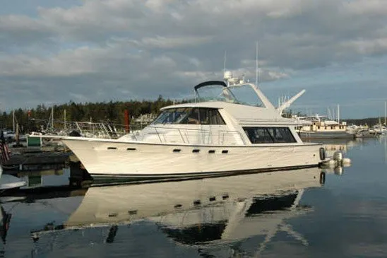 Slide: The Image of 2000 Bayliner 4788 Pilot House Motoryacht docked in a serene marina setting. - 1