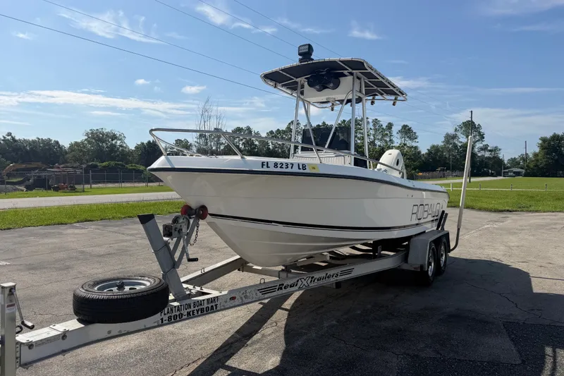 Slide: The Image of 1999 Robalo 2120 Center Console boat on trailer, parked outdoors under clear sky. - 4