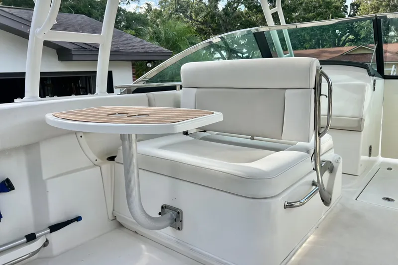 Slide: The Image of 2015 Boston Whaler 270 Vantage boat interior with cushioned seating and wooden table. - 85