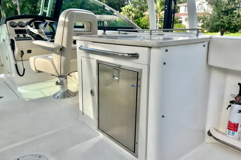 Slide: The Image of 2015 Boston Whaler 270 Vantage interior with helm, seating, and stainless steel kitchenette. - 84