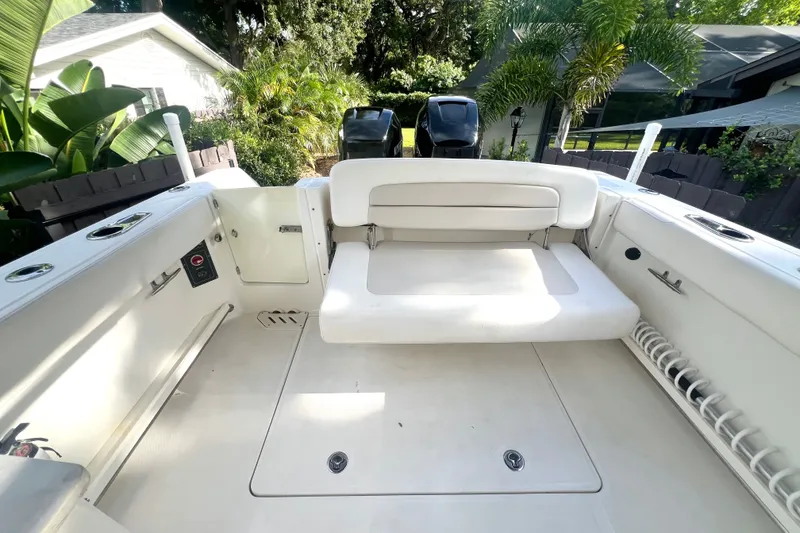 Slide: The Image of 2015 Boston Whaler 270 Vantage boat interior with seating and storage, surrounded by lush greenery. - 49