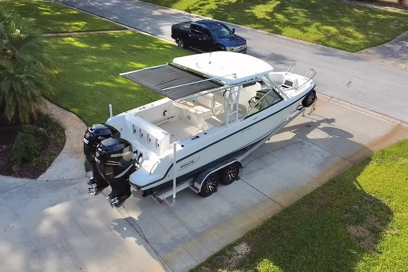 Slide: The Image of 2015 Boston Whaler 270 Vantage boat on trailer, parked in driveway, with twin Mercury engines. - 33