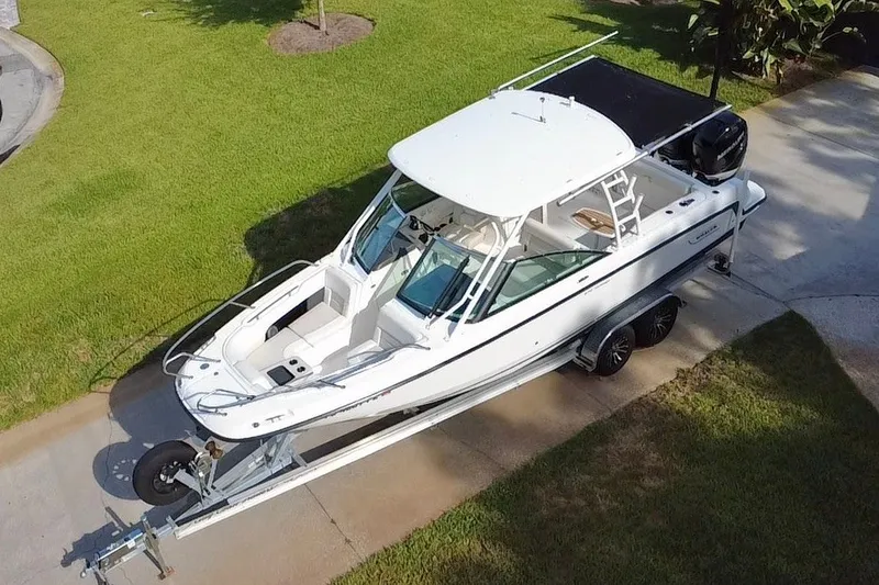 Slide: The Image of 2015 Boston Whaler 270 Vantage boat on trailer, parked on driveway, surrounded by grass. - 28