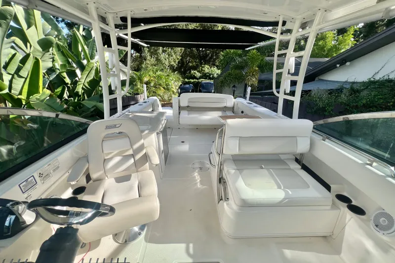 Slide: The Image of 2015 Boston Whaler 270 Vantage boat interior with seating and steering wheel, surrounded by lush greenery. - 53