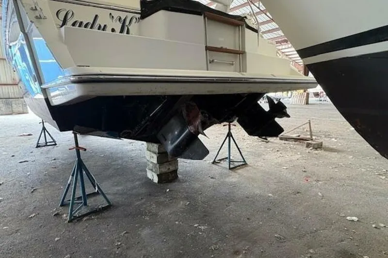 Slide: The Image of 1991 Carver 3067 Santego boat on stands in a warehouse, showing propellers. - 8