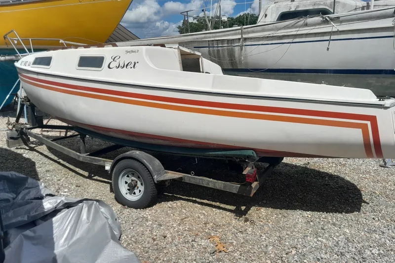 The Image of 1979 Clark San Juan sailboat on trailer, white with orange stripes, named "Essex." - 0