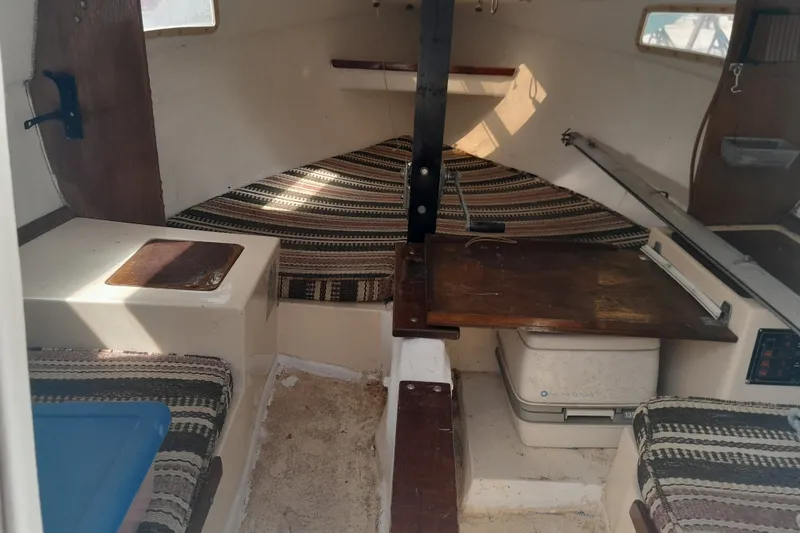 Slide: The Image of Interior of a 1979 Clark San Juan sailboat with striped cushions and wooden table. - 5