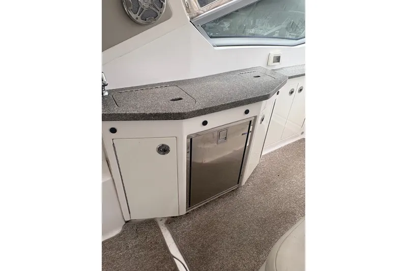 Slide: The Image of 2015 Chaparral 310 Signature boat interior with kitchenette and storage cabinets. - 10
