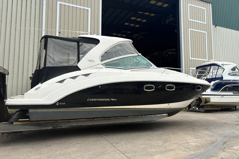 Slide: The Image of 2015 Chaparral 310 Signature boat docked outside a large warehouse. - 0