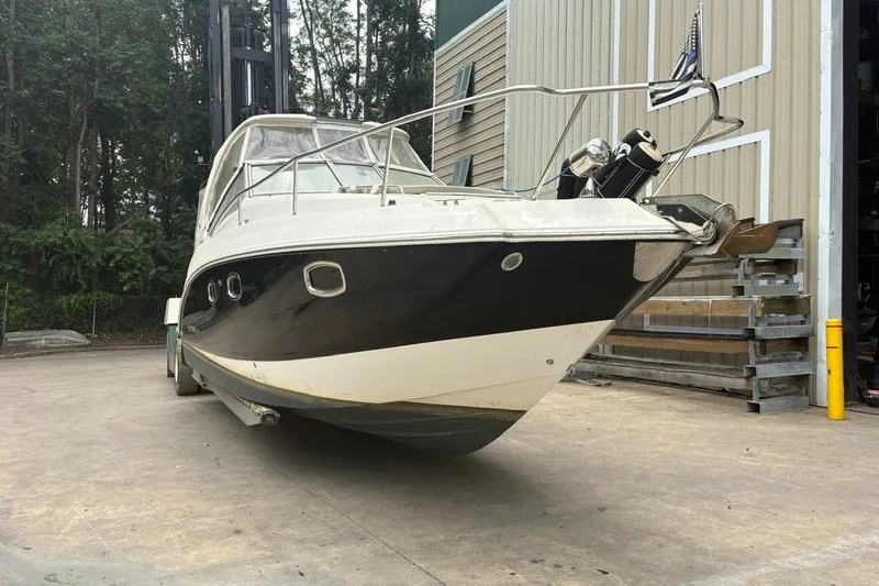 Slide: The Image of 2015 Chaparral 310 Signature boat on dry dock, surrounded by trees and industrial buildings. - 1