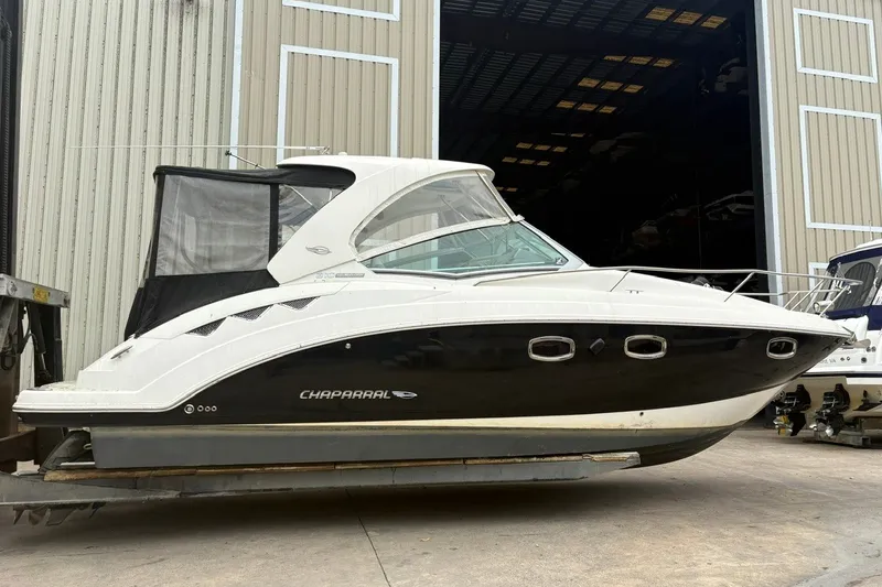 Slide: The Image of 2015 Chaparral 310 Signature boat in storage, featuring sleek black and white design. - 2