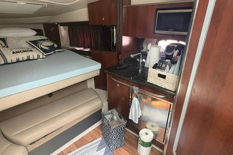 Slide: The Image of 2015 Chaparral 310 Signature cabin interior with bed, kitchenette, and storage. - 9