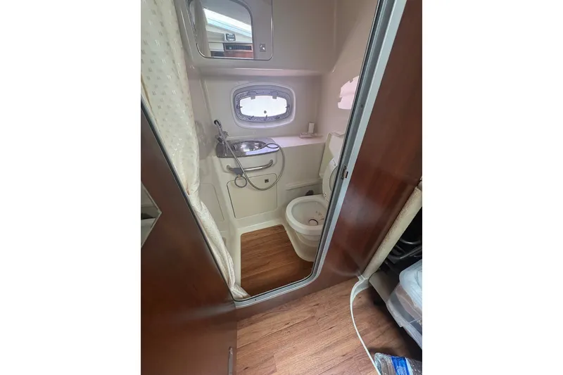 Slide: The Image of 2015 Chaparral 310 Signature boat bathroom with sink, toilet, and porthole window. - 6