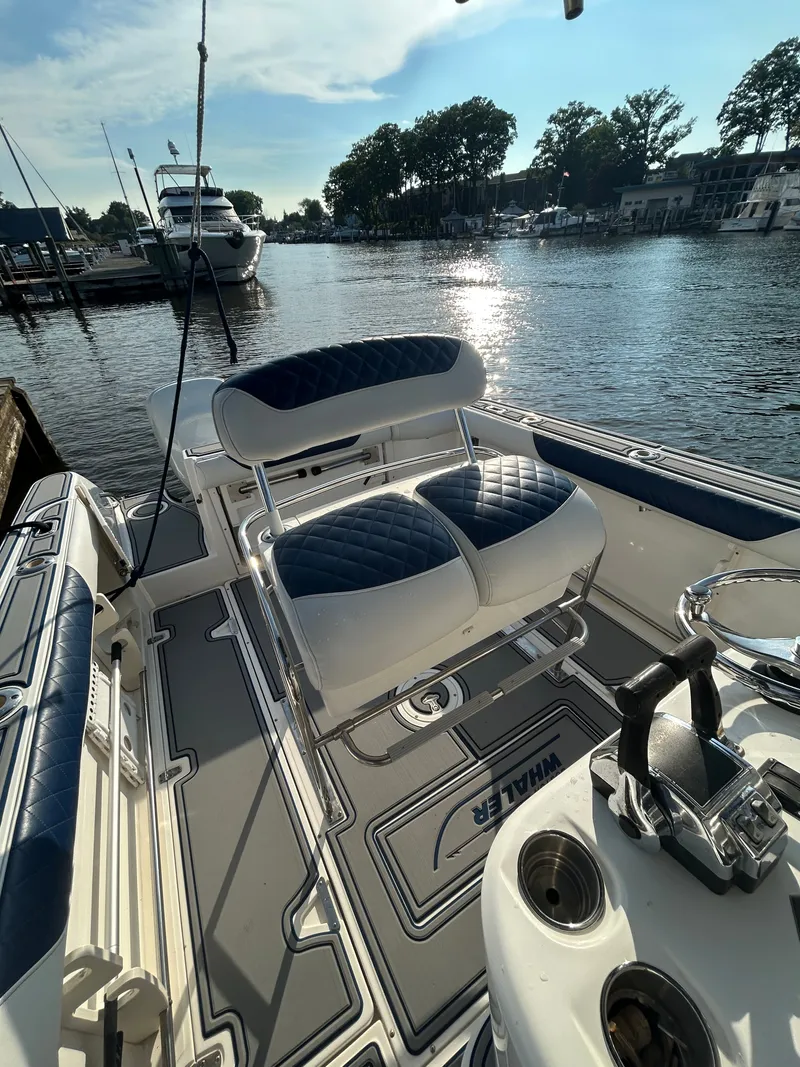 Slide: The Image of A 2004 Boston Whaler 270 Outrage docked. It features cushioned seating and a helm console. - 7