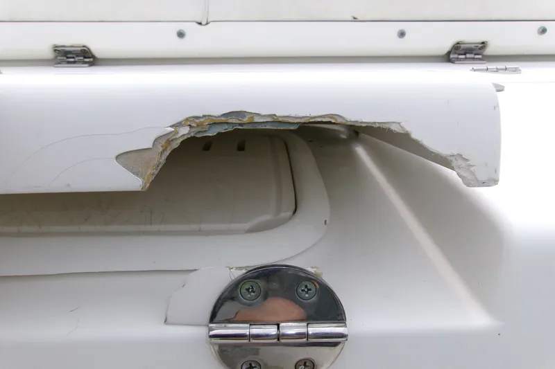 Slide: The Image of Damaged section on 2010 Robalo R240 Center Console boat, showing chipped fiberglass near hinge. - 18