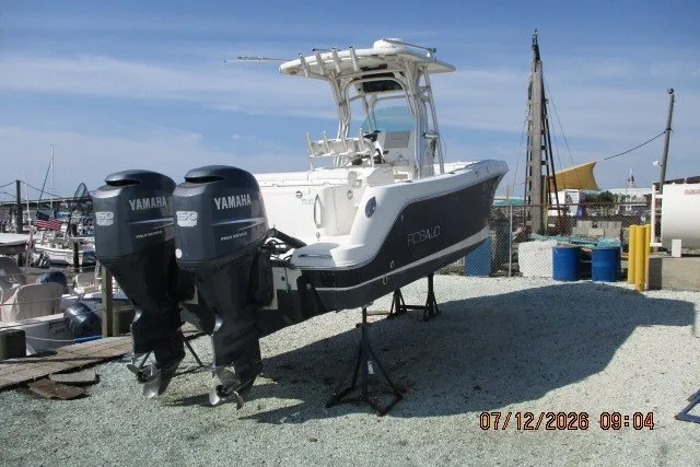 Slide: The Image of 2010 Robalo R240 Center Console boat with twin Yamaha engines on a gravel lot. - 2