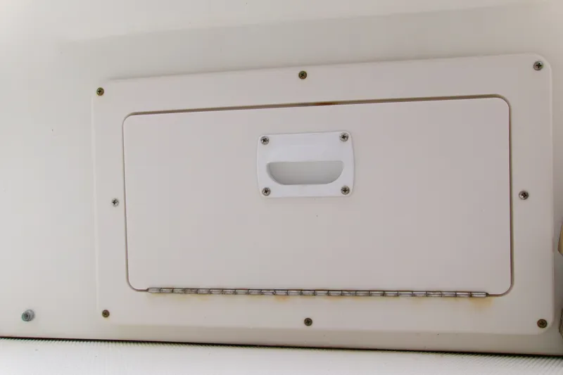 Slide: The Image of 2010 Robalo R240 Center Console storage compartment with white hatch and handle. - 33