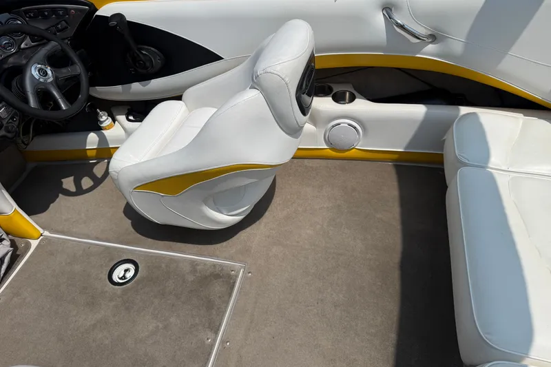 Slide: The Image of 2007 Crownline 21 SS boat interior with white and yellow seating, steering wheel, and carpeted floor. - 21