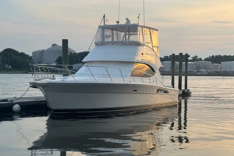 Slide: The Image of 2009 Riviera 45 Open Flybridge yacht docked at sunset, reflecting on calm water. - 2