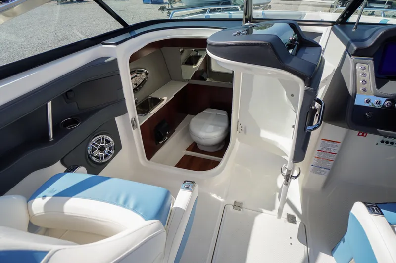 Slide: The Image of 2026 Chaparral 270 OSX boat interior with helm, seating, and compact cabin toilet. - 30