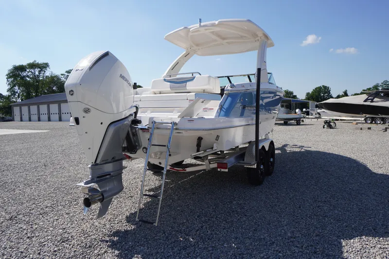 Slide: The Image of 2026 Chaparral 270 OSX boat with outboard motor on a gravel lot under clear sky. - 76