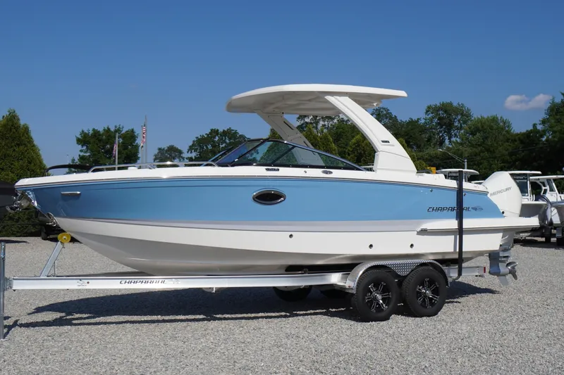 The Image of 2026 Chaparral 270 OSX boat on trailer, blue and white design, parked outdoors. - 0
