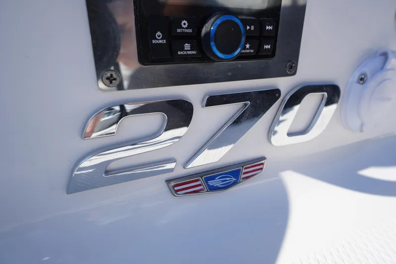 Slide: The Image of 2026 Chaparral 270 OSX boat dashboard with chrome model emblem and control panel. - 60